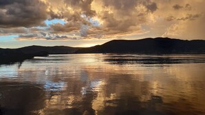 A calm lake with mountains in the background and a cloudy sky.