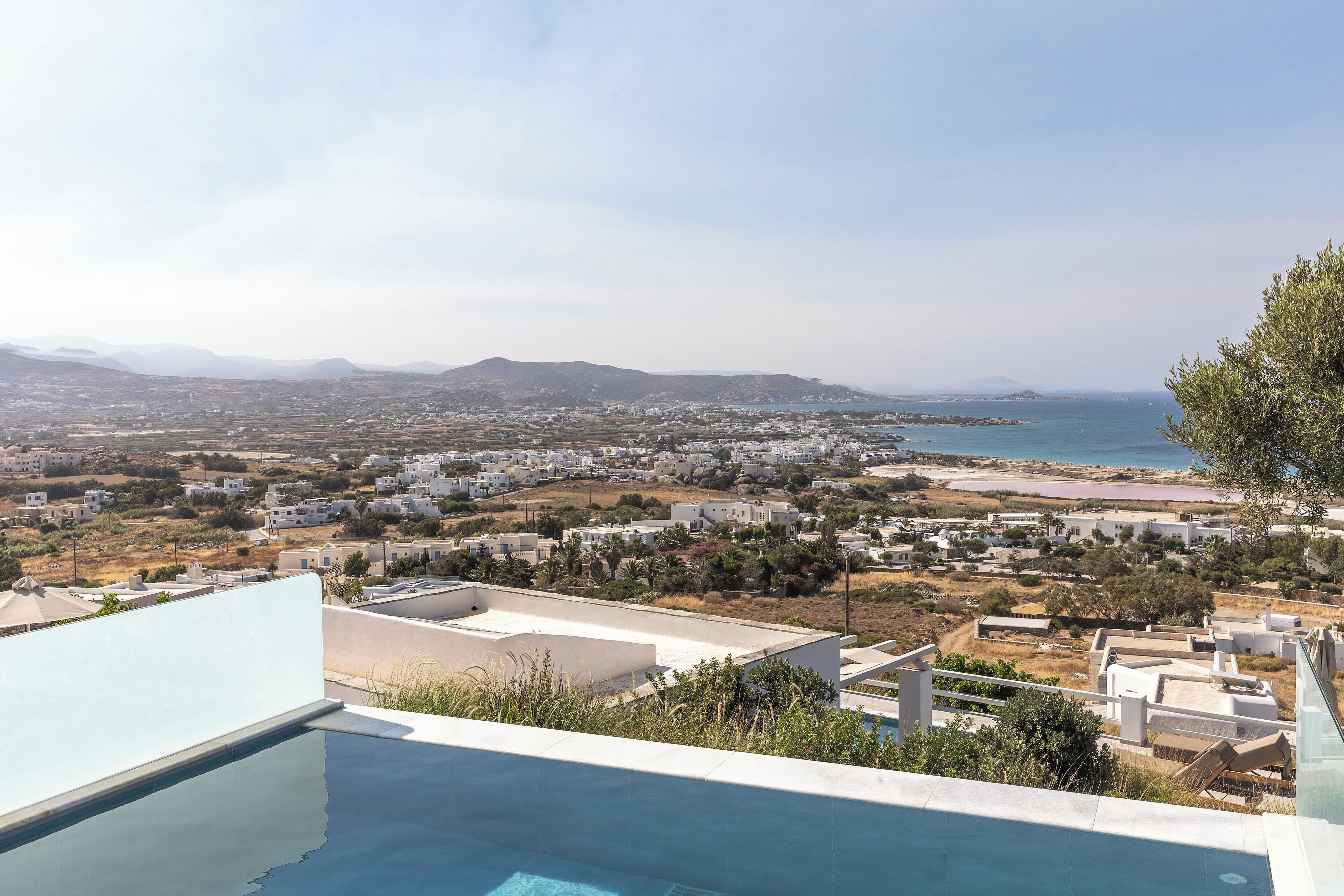 Una piscina en la azotea con vistas a un pueblo costero y montañas lejanas.