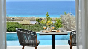 A poolside table with drinks and a plate, overlooking a clear blue sea and distant mountains. - Mythology Naxos Villas & Suites (Naxos)