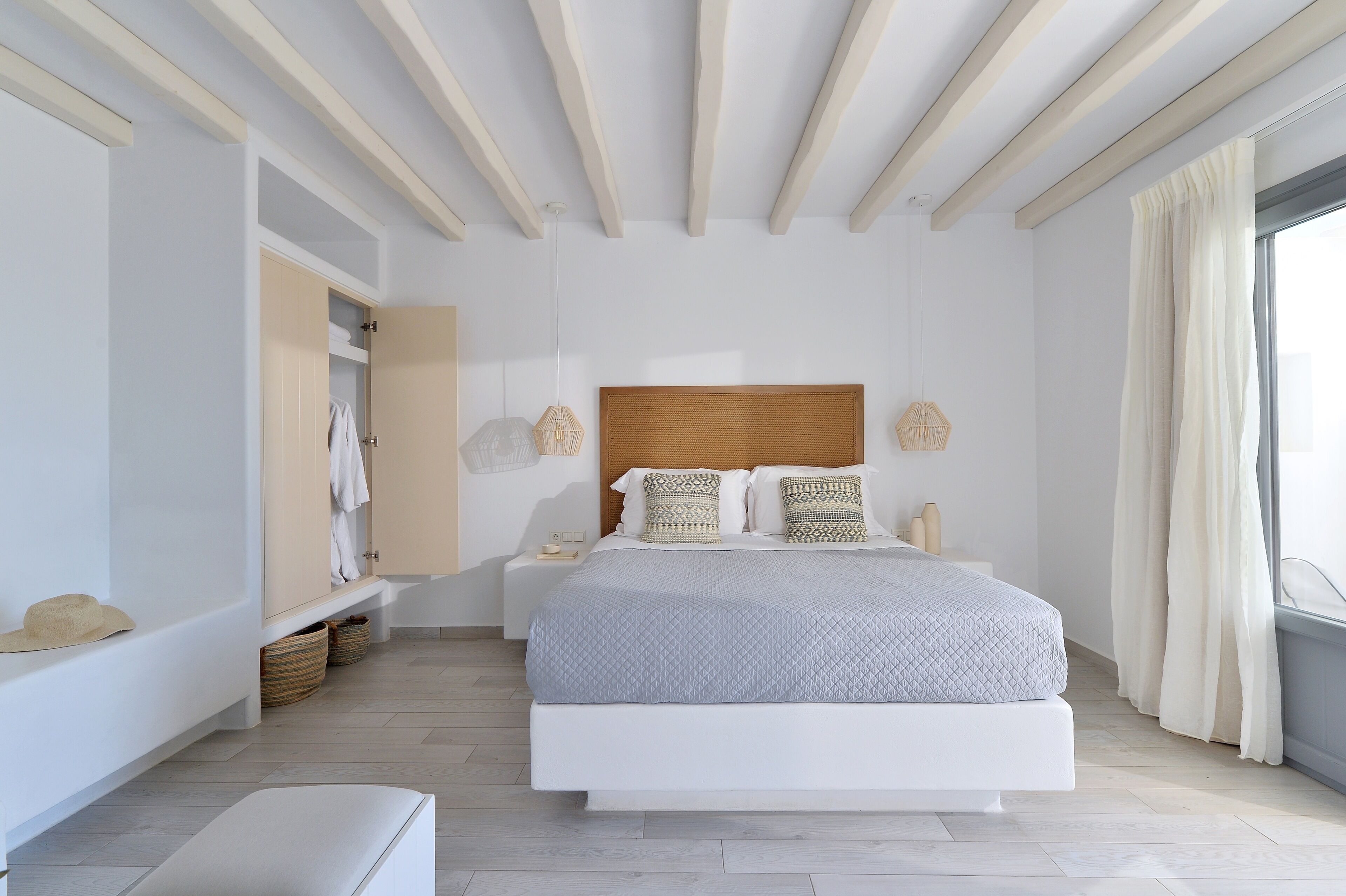 A modern bedroom with a large bed, a wooden headboard, and a window with curtains.
