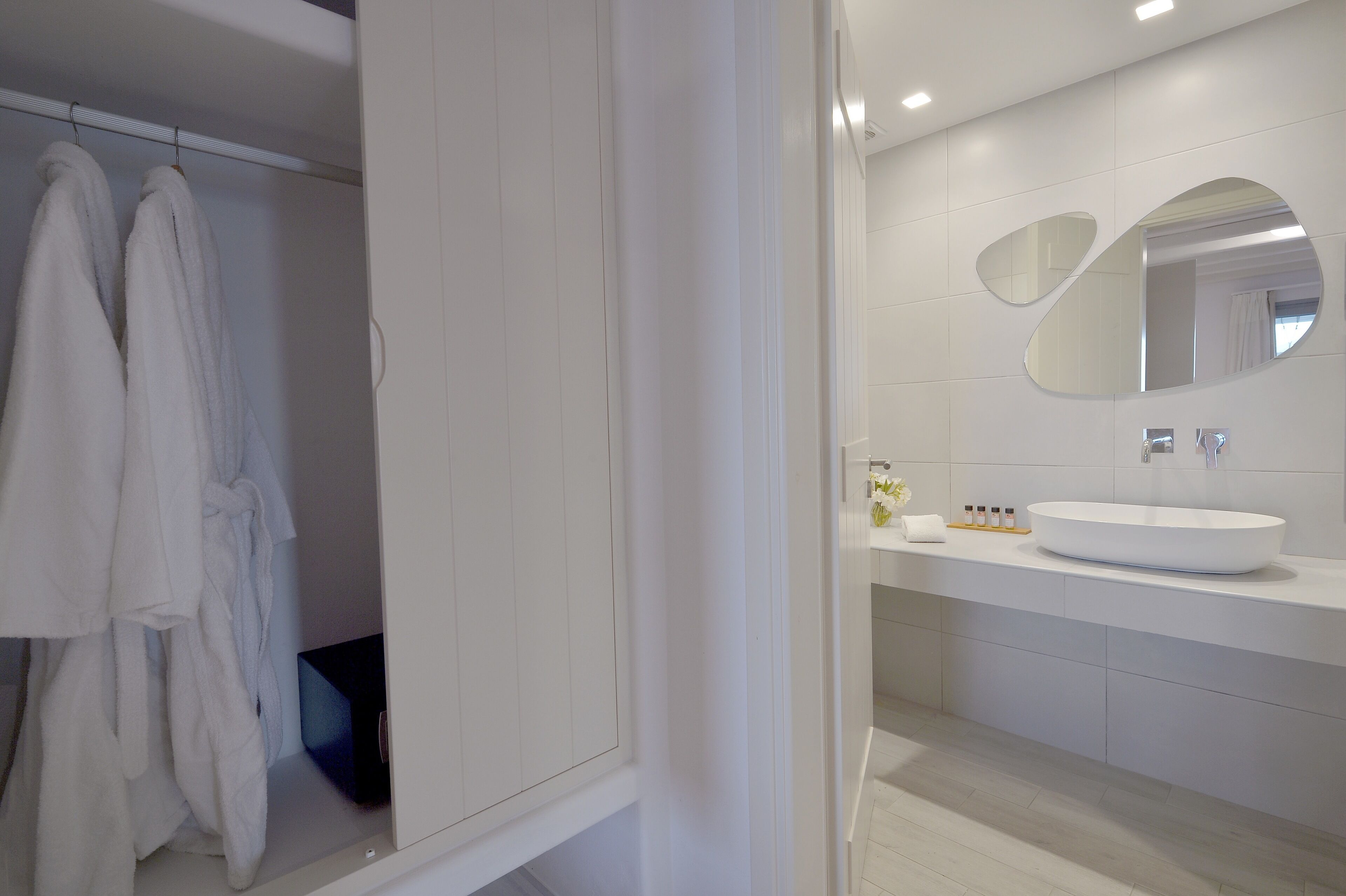 Un baño moderno con un tocador blanco, un espejo grande y un perchero para toallas.