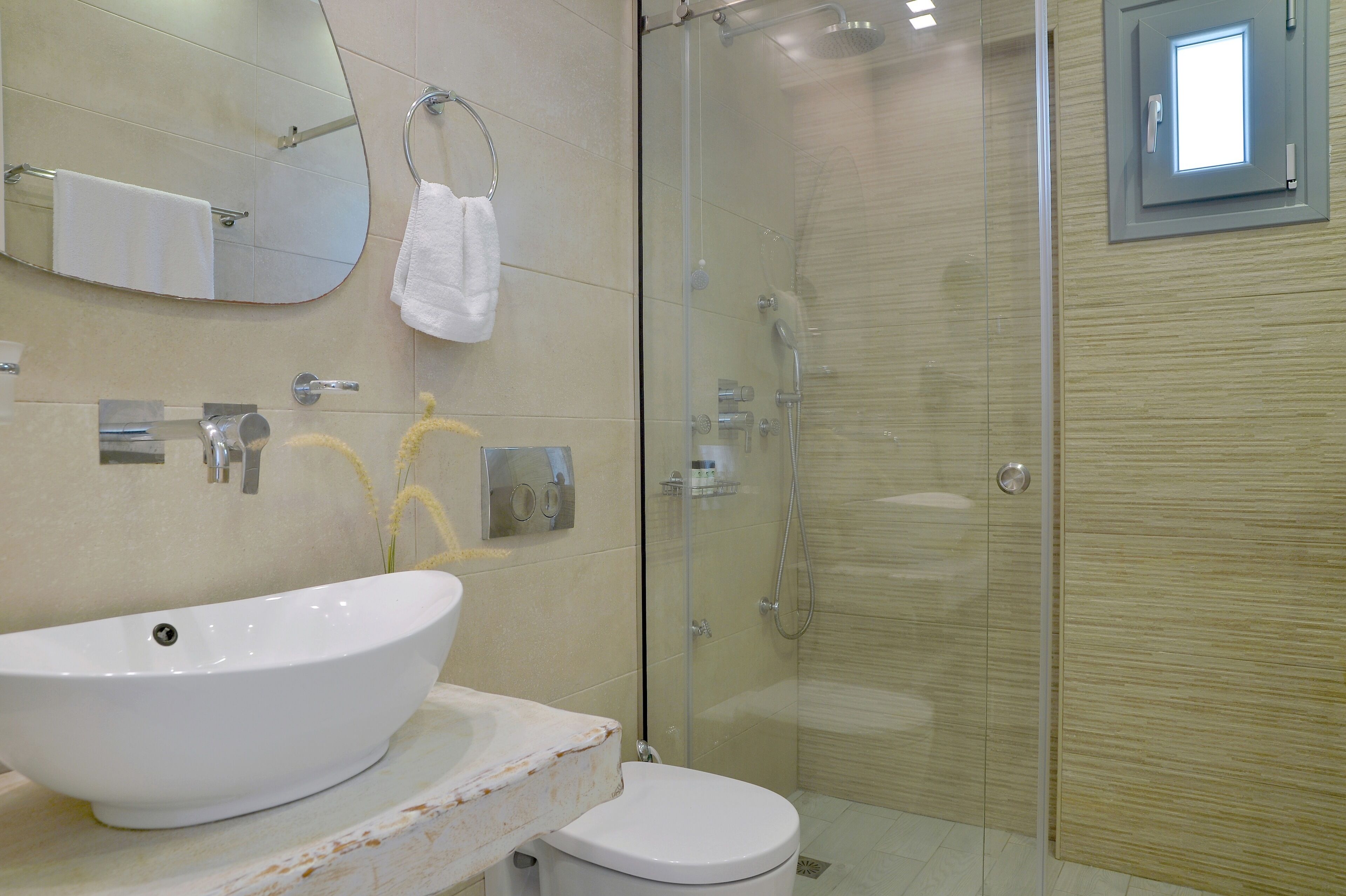 Ein Badezimmer mit einem großen weißen Waschbecken, einer Toilette, einer Duschkabine und einem Spiegel über dem Waschbecken.