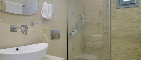 Een badkamer met een groot wit wastafel, toilet, douche met glazen wanden en een spiegel boven het wastafel.