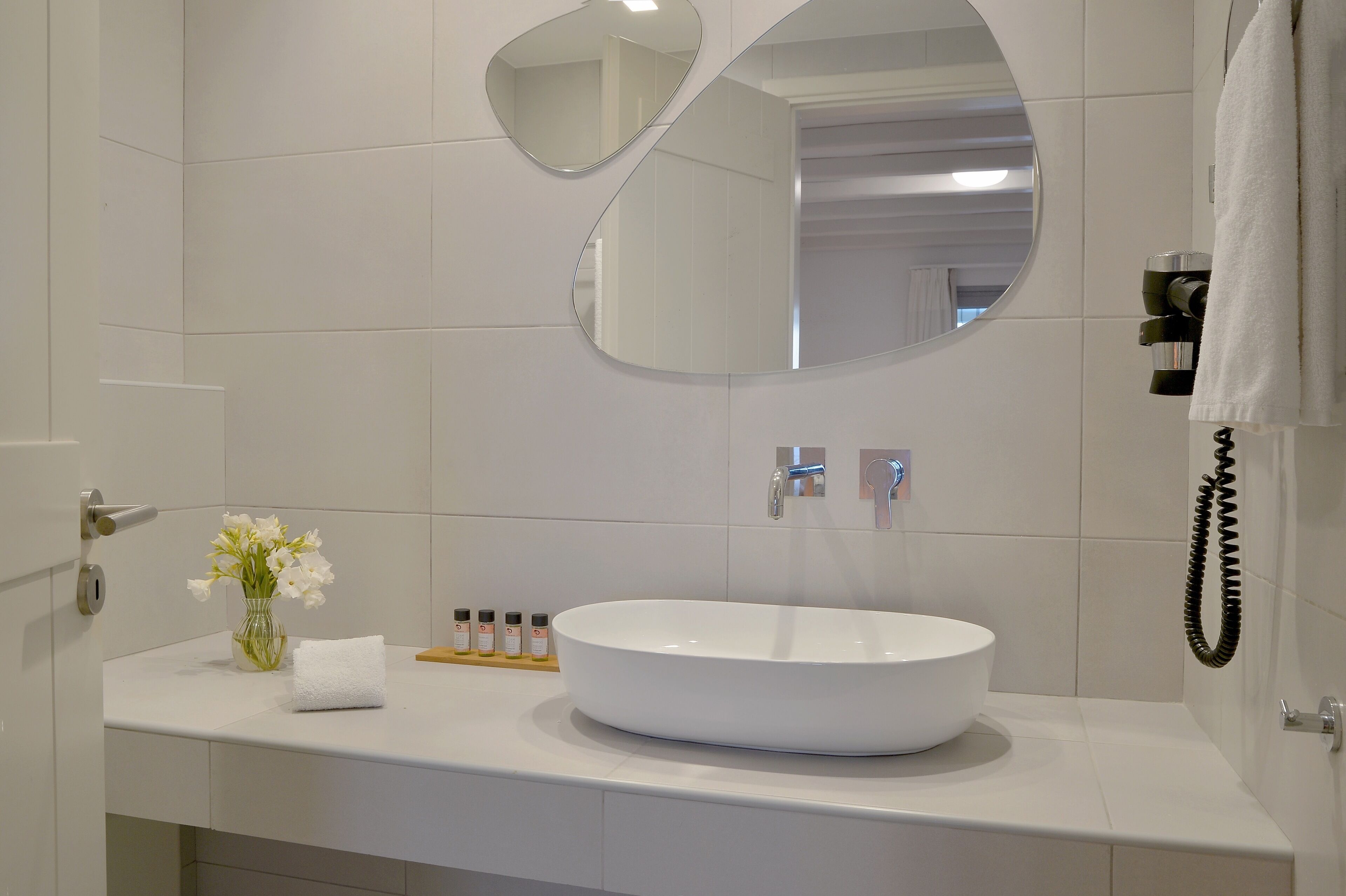 Et moderne badeværelse med en stor, oval håndvask, et spejl og en håndklædeholder.