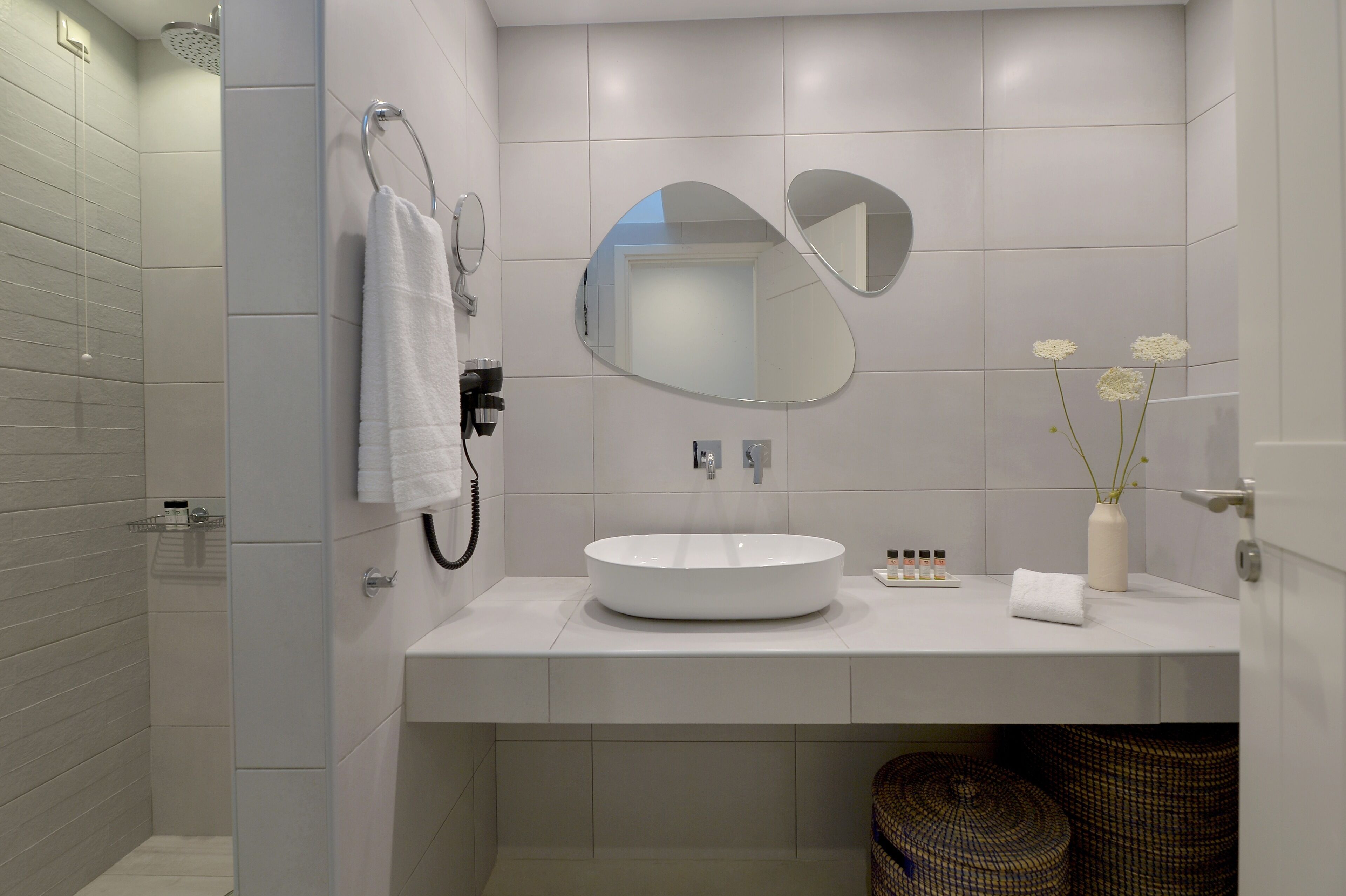 A modern bathroom with a large mirror, a round sink, and a towel rack.