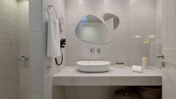 A modern bathroom with a large mirror, a round sink, and a towel rack.