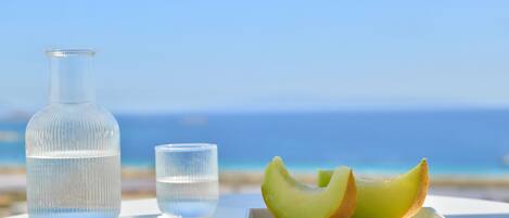 A table with a glass bottle and a glass of water, and a plate with melon slices.