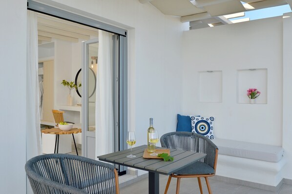 A modern outdoor dining area with a table, chairs, and a bottle of wine.