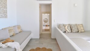 A modern, minimalist room with two sofas, a wall-mounted air conditioner, and a hallway leading to a bathroom. - Mythology Naxos Villas & Suites (Naxos)