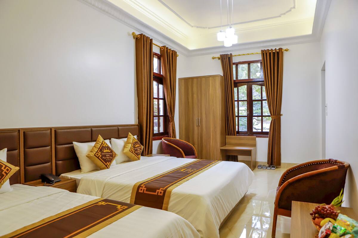 A hotel room with two beds, a wooden headboard, a desk, and a chair.
