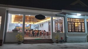 A restaurant with a dining area visible through large windows, a covered outdoor seating area, and a gated entrance. - Van Xuan Royal Hotel (Ninh Binh)