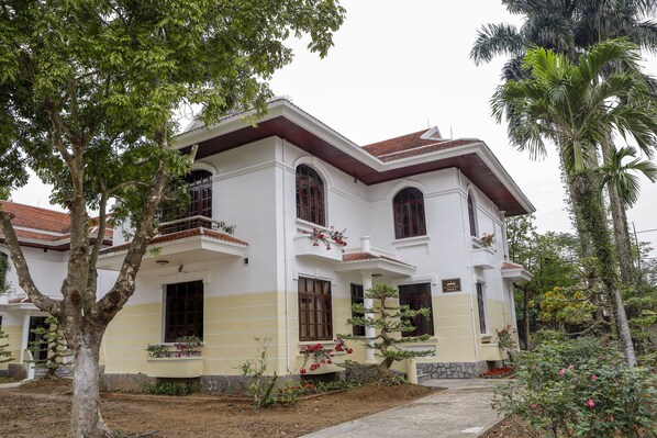 A two-story house with a balcony, surrounded by trees and plants. - Van Xuan Royal Hotel (Hoa Lu)