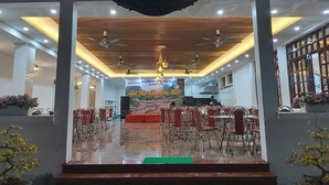 A restaurant with a stage in the center, surrounded by tables and chairs. - Van Xuan Royal Hotel (Ninh Binh)