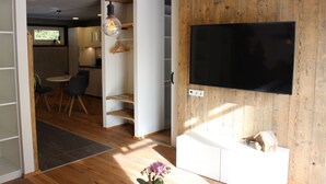 Ett modernt kök med träskåp, en matplats med stolar och en TV som är monterad på en trävägg.