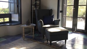 Une pièce avec une fenêtre, une chaise, une petite table et une porte.