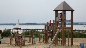 A beach playground with a wooden play structure and a slide.