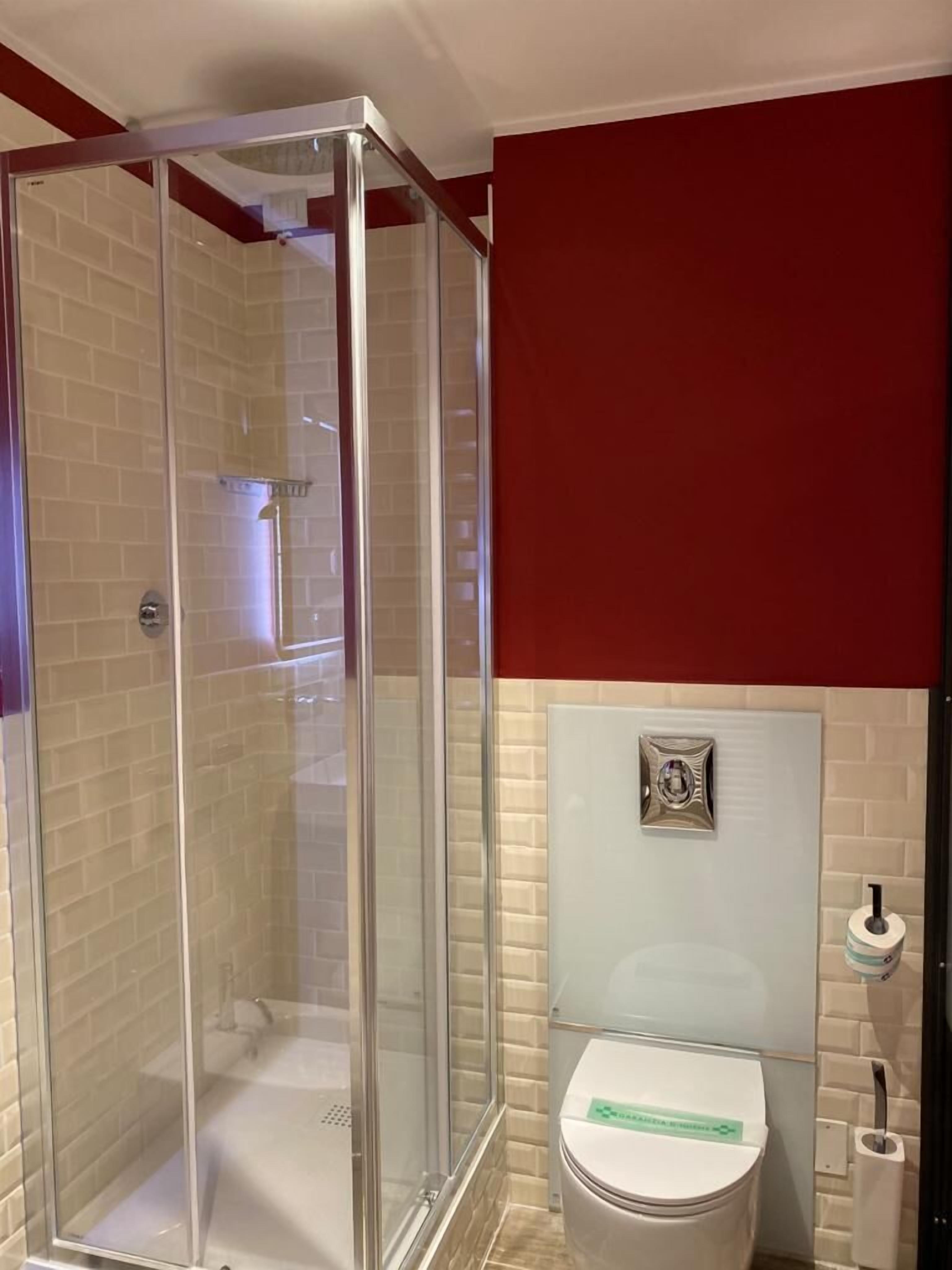 Un baño con ducha envuelta en vidrio, inodoro y lavamanos.