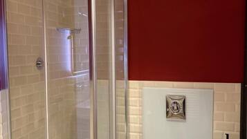 A bathroom with a glass-enclosed shower, a toilet, and a sink.
