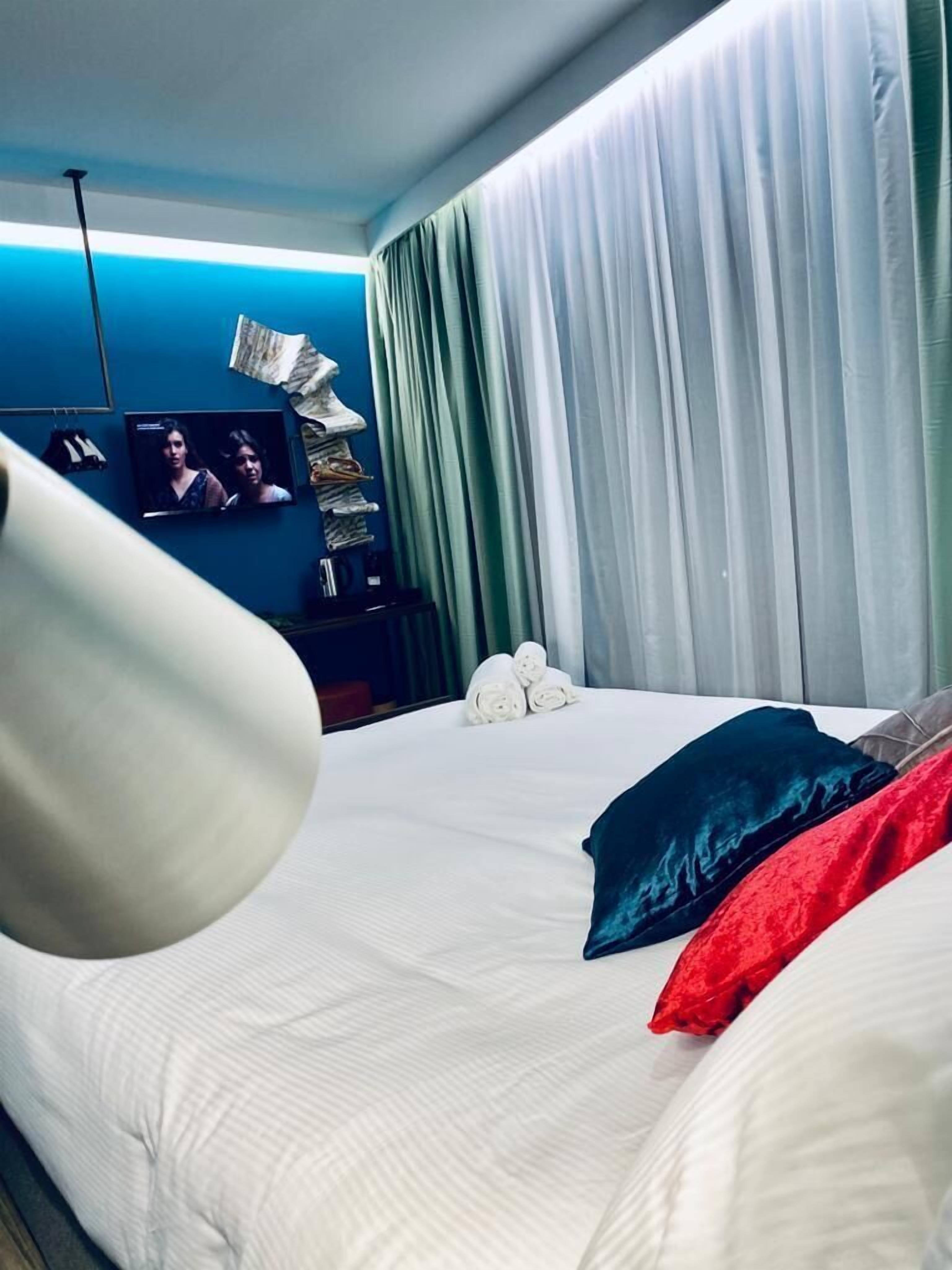 A hotel room with a bed, a television, and a window with curtains.