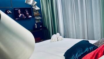 A hotel room with a bed, a television, and a window with curtains.