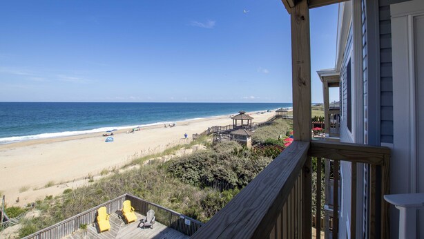 A wooden deck overlooking a beach with a gazebo and lounge chairs. - OCEANFRONT, Community Pool and beach walkway! KD220, Feelin Nauti (Kill Devil Hills)