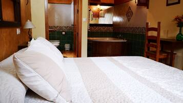 Una habitación de hotel con cama, baño con lavamanos y una silla.