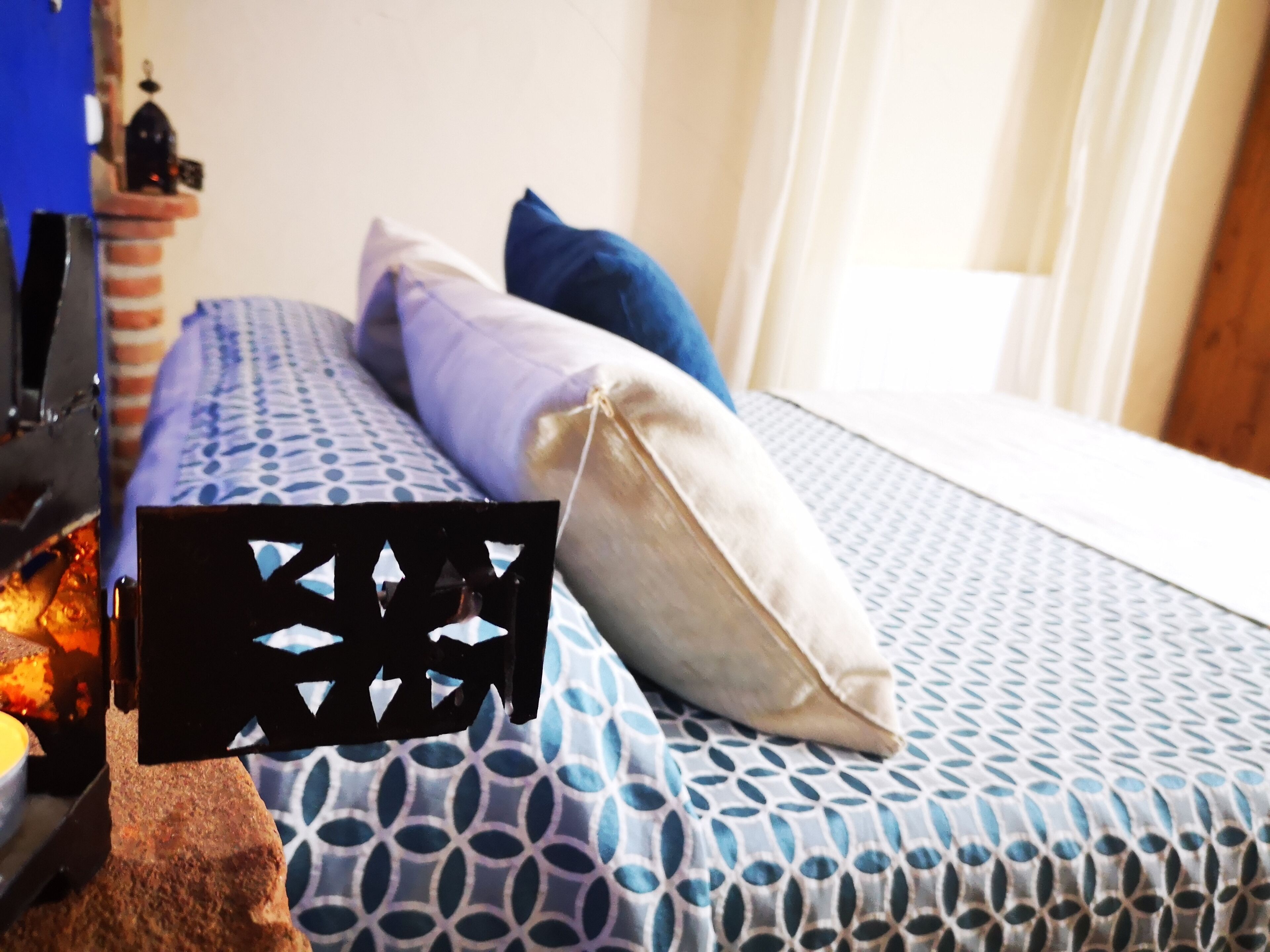 A bed with a patterned bedspread, pillows, and a black headboard.