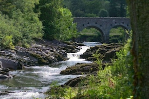 A river flowing under a stone bridge surrounded by lush greenery. - Dunkerron Woods 3 Bedroom 4030 (Kenmare)