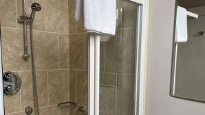 A shower with a white towel, a glass door, and a chrome showerhead. - Dunkerron Woods 3 Bedroom 4027 (Kenmare)