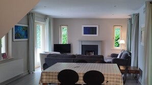 A living room with a fireplace, a television, a sofa, a table, and a lamp. - Dunkerron Woods 3 Bedroom 4027 (Kenmare)