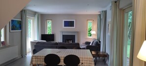 A living room with a fireplace, a television, and a sofa. - Dunkerron Woods 3 Bedroom 4027 (Kenmare)