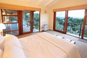 Een slaapkamer met een groot bed, een balkon en uitzicht op de omgeving.