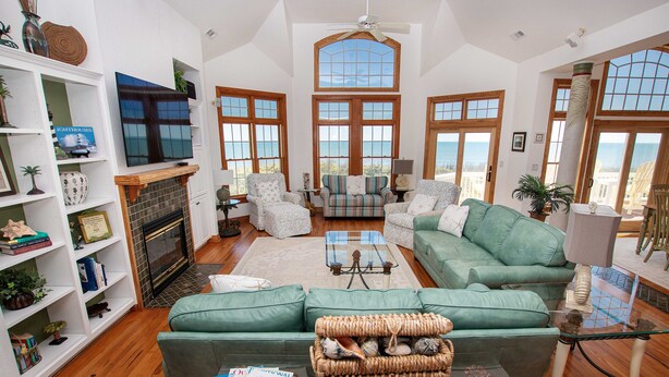 A spacious living room with a fireplace, large windows, and a view of the ocean. - OCEANFRONT, Ocean views, Rec Rm, Private Pool, Hot Tub, PI52, Coco Palms (Corolla)