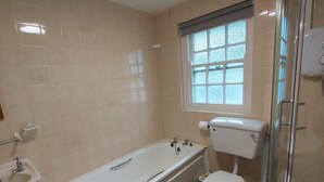 A bathroom with a bathtub, toilet, and a glass-enclosed shower. - Corofin Lake Cottage No 2 (Killinaboy)