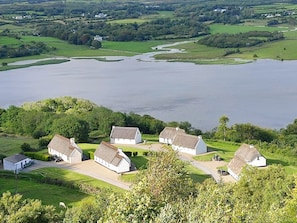 A coastal village with white houses, a river, and a large body of water. - Corofin Lake Cottage No 2 (Killinaboy)