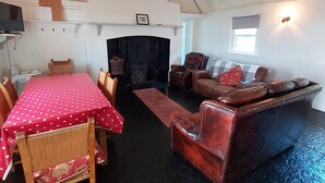 A spacious living area with a fireplace, a dining table with chairs, and a leather sofa. - Corofin Lake Cottage No 2 (Killinaboy)