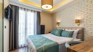 Une chambre d’hôtel avec un grand lit, un bureau en bois, une télévision et un mur en briques.