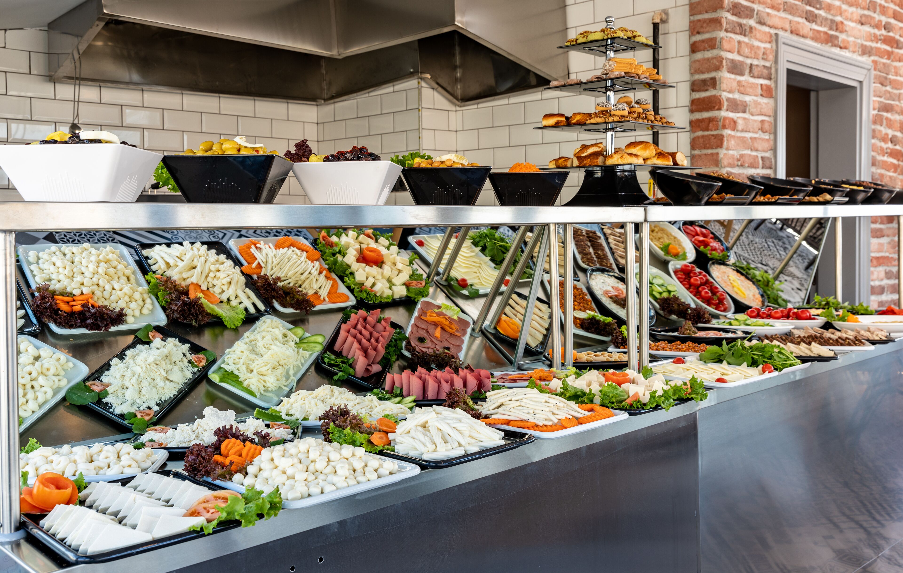 Buffet com diversos alimentos, incluindo saladas, carnes e queijos.