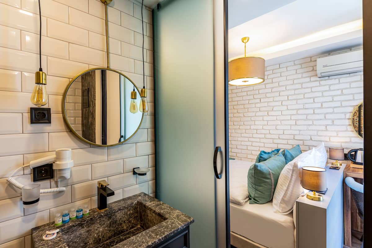 A modern bathroom with a marble sink, a round mirror, and a hairdryer.