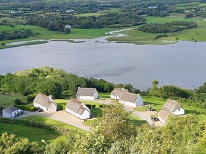 A coastal village with white houses, a river, and a large body of water. - Corofin 3 bed No 5 (Killinaboy)