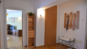 A room with a wooden wardrobe, a bench, a shelf with plants, and a desk with a chair. - Victoriei 7 - 2 bedroom apartment downtown (Sector 1)