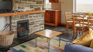 Ein gemütliches Wohnzimmer mit Kamin aus Stein, Holzboden und einem Essbereich mit Holzmöbeln.