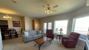 A living room with a sofa, armchair, coffee table, dining table, chairs, and a ceiling fan. - Greenview Getaway by Mesquite Vacation Rentals at Wolf Creek Golf Course Condo with $510 in free daily activities (Mesquite)