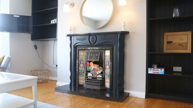Una habitación con chimenea, espejo y estantes con objetos decorativos.