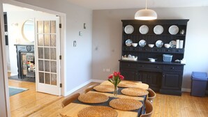 Un comedor con una mesa de madera, individuales tejidos y un jarrón de flores.