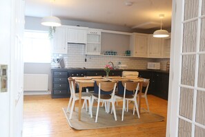 A kitchen with white cabinets, a wooden dining table with chairs, and pendant lights.