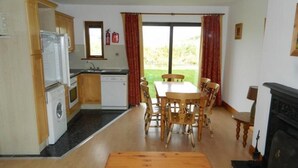 A compact kitchen with a dining area, a washing machine, and a fireplace. - Kinsale No 6 (Kinsale)