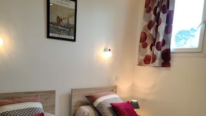 A bedroom with two beds, a poster on the wall, and a window with curtains. - The PENTY, AR-MEN an independent holiday home  (Garlan)