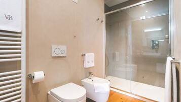 A modern bathroom with a toilet, bidet, and glass-enclosed shower.