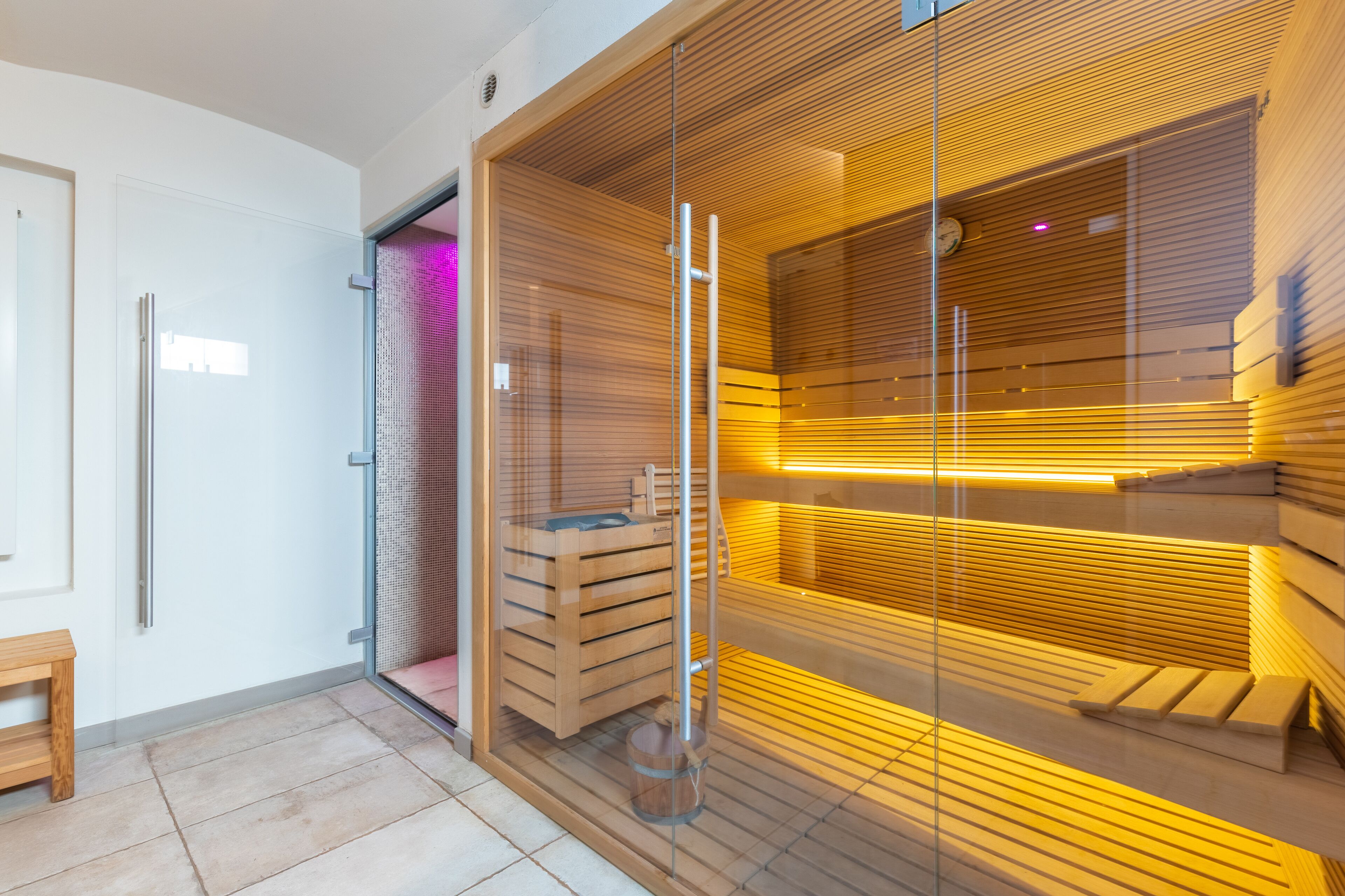 Uma sauna moderna com bancos de madeira e divisória de vidro.